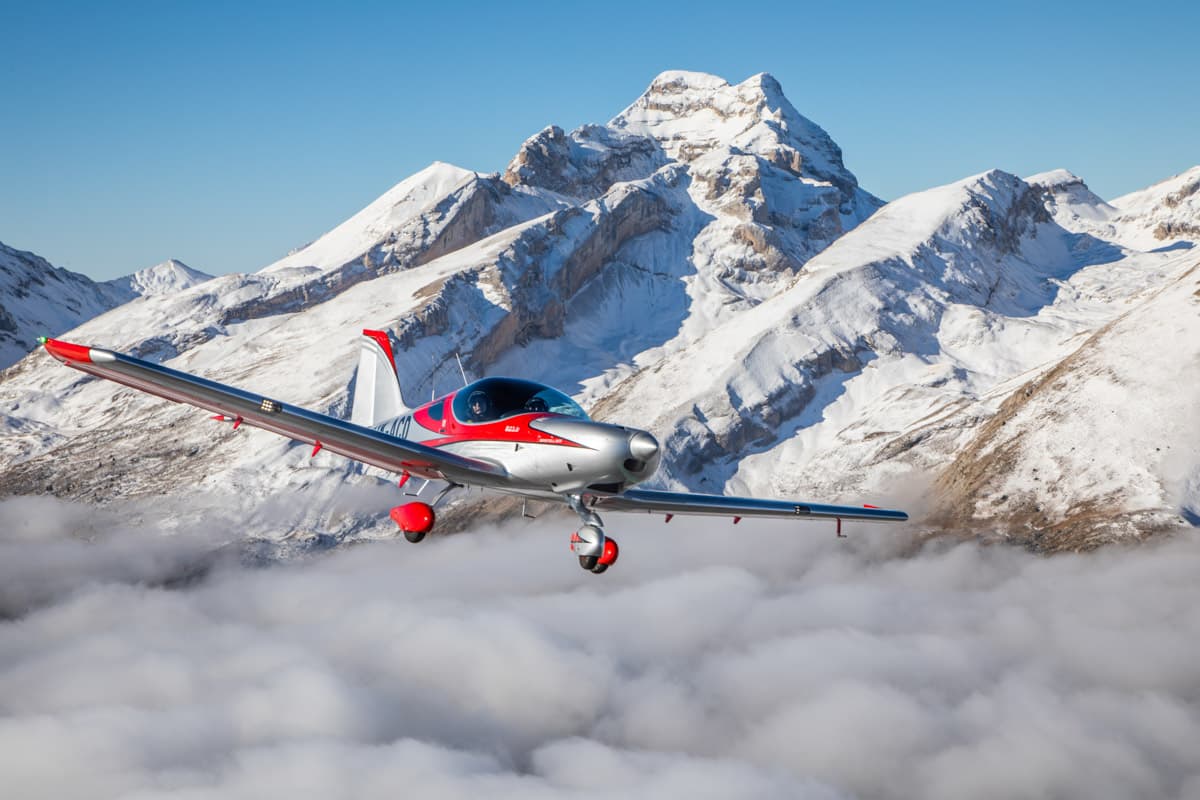 Bristell B23 above the clouds beside a snow-capped peak